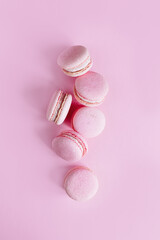 Tasty french macarons on a pink pastel background.