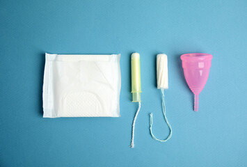 Tampon, pad and menstrual cup on blue background, flat lay © New Africa