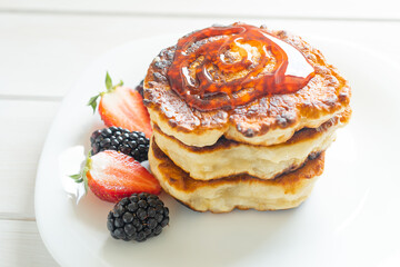 pancakes on a light background with jam and berries