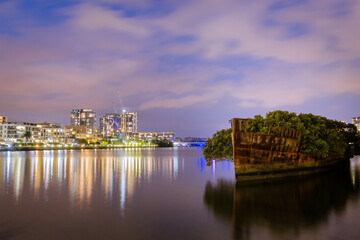 Shipwreck on river with cityscape long exposure