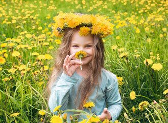 Joyful child on a grassy lawn wearing a dandelion wreath