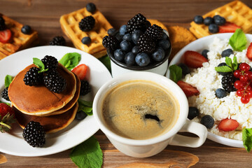 Waffles with blueberries and raspberries on plate. Cottage cheese, Coffee and berries on wooden background.