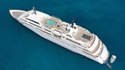 Aerial drone photo of luxury mega yacht with wooden deck and pool facilities anchored in Mediterranean open ocean deep blue bay