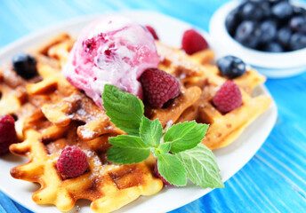 Belgian waffles with fresh berries and ice cream over blue wooden background