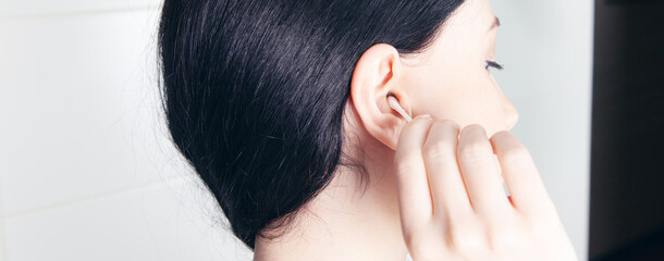 Fototapeta premium young woman cleans her ear with a cotton swab