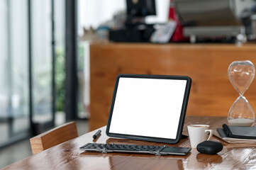 Mockup blank screen tablet with keyboard on wooden table in cafe room.