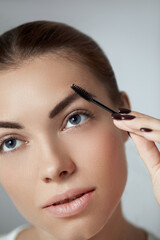 Fototapeta premium Young beautiful woman correcting shape of eyebrows. Contouring Eyebrow makeup .