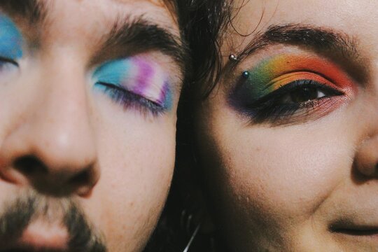 portrait of closeup faces of two lgbtq queer friends faces with rainbow pride flag and trans pride flag makeup *2