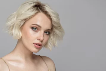 Fotobehang Portrait of a beautiful blonde girl with a short haircut. Gray background. © yuriyzhuravov