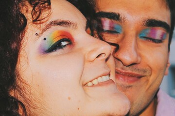 happy smiling portrait of two lgbtq gender queer friends with rainbow pride flag and trans pride flag eye makeup with eyebrow piercing - obrazy, fototapety, plakaty