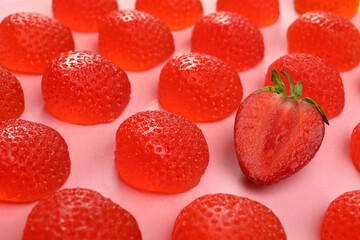 Delicious gummy candies and fresh strawberry on pink background, closeup
