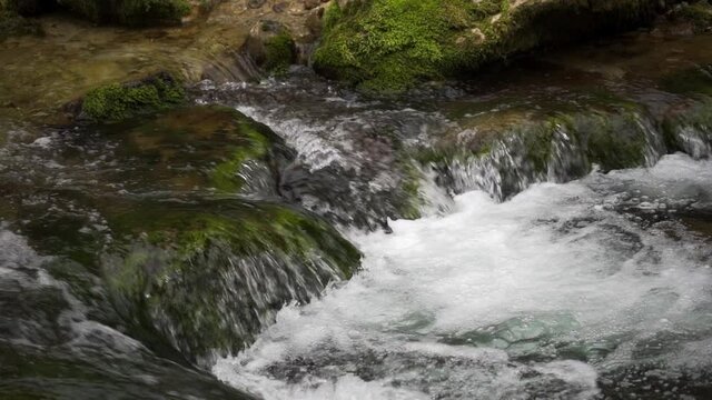 Cold mountain river in the forest. Water flows over large stones. Solitude with nature. Close-up, slow motion, HD.