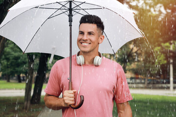 Man with umbrella walking under rain in park