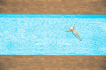 Young alone beautiful sports woman in bikini and hat is swimming in swimming pool. Aerial drone view from above. Tropical summer vacation