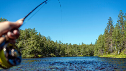 Fly fishing rod in fisherman hand. Fishing on the mountain river. Summer Activities.