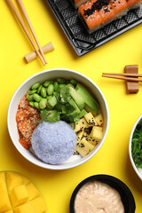 Delicious sushi rolls and poke bowls on yellow background, flat lay