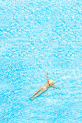 Top view of young woman in bikini and straw hat is swimming in transparent blue sea, lagoon....