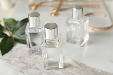 Bottles of essential oil on white marble table, closeup