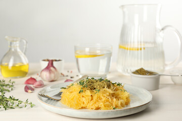 Tasty spaghetti squash with pesto sauce and thyme served on white wooden table