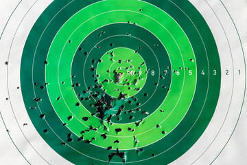 Green archery target all covered with arrow holes