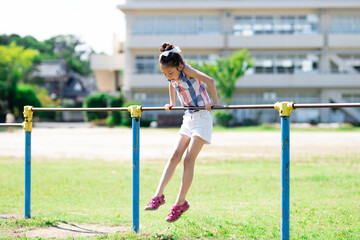 校庭で鉄棒をする少女