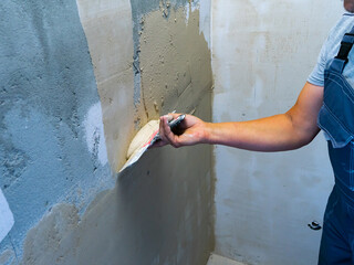 House improvement by worker. Hand with a spatula. Worker trowels putty on wall with finishing putty.
