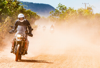 Man riding his adventure motorbike on dusty road in Cambodia