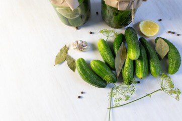 Cooking preserve in Glass jar with fermented cucumbers with lemon, herbs, spices on white background