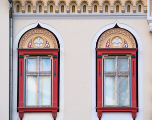 Fototapeta na wymiar Detail with a beautiful restored old building in timisoara Romania. Architectural detail of two colred wooden framed window