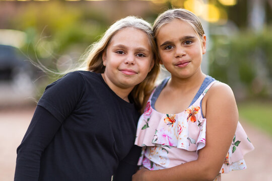 two young aboriginal girls outside with heads together