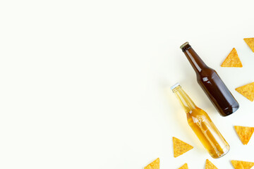 A two bottles of craft lager and porter beer and nachos snack on ivory background. International beer day or Octoberfest concepts.Resting and Drinking beer. Minimalistic photo.Copy space