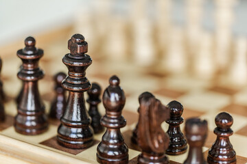 Wooden chess pieces set up on board game indoors
