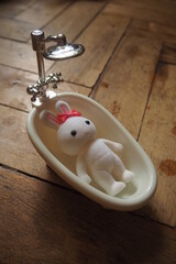Malutka zabawka biały króliczek w miniaturowej wannie  - obrazy, fototapety, plakaty