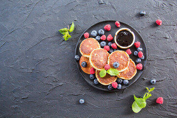 Obraz na płótnie Canvas A healthy breakfast of cheese pancakes, berries, and honey. Creative atmospheric decoration