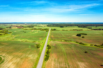 Highway through fields and arable land. View from above. Summer rural landscape