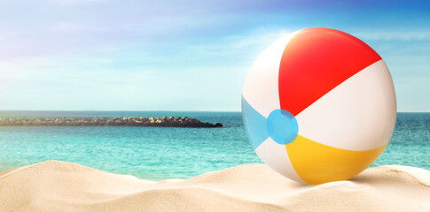 Fototapeta na wymiar Colorful beach ball on sandy coast near sea, space for text. Banner design