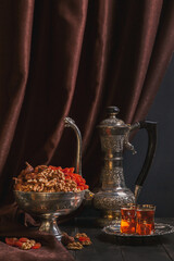 Vintage jug for water or tea, vase with dried fruit and a plate with tea in armuda glasses