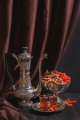 Ancient East metallic crockery - vintage jug, vase with dried fruit and a plate with tea in armuda...