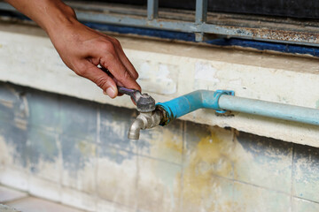 Hand is turning off old faucet in the factory. Concept : Save water for living and for life.        