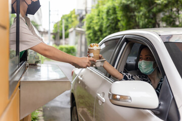 Woman customer in protective mask picking up cup of coffee at driving through.