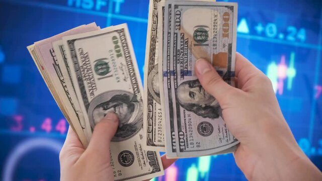 Hands counting dollar bills. stock market graphs in the background. making easy money from stock market trading and investing. rich and wealthy NFT. Close up of American money