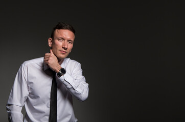 portrait of a man. Young business man in shirt and tie looking at camera. Portrait businessman on a dark background with copy space.