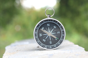 Classic navigation compass on natural background as symbol of tourism with compass, travel with...