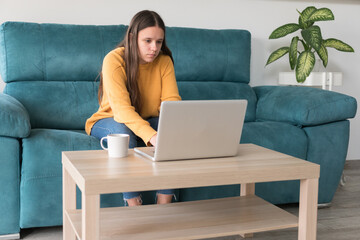 girl with laptop and cup of coffee on the sofa