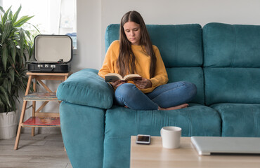 girl reading a book sitting on the sofa