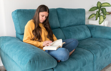girl reading a book sitting on the sofa