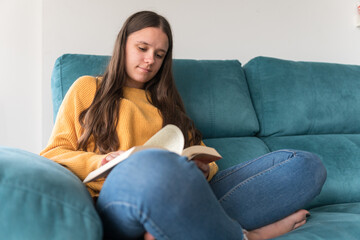 girl reading a book sitting on the sofa