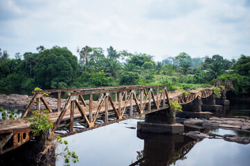 Fototapeta na wymiar Rusty old steel bridge over an river in the central african tropical rain forest