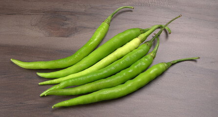 Fresh long Indian green chillies on wooden background.