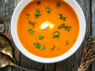 Cream tomato soup with fresh parsley on wooden table
